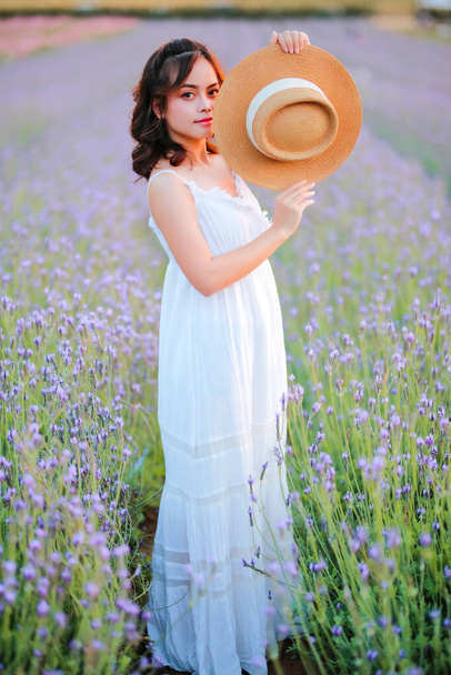 Blond long haired woman in lavender field. Style life enjoying journey to travel on vacation with relaxation with in long white dress outdoors on summer day. - Foto, imagen