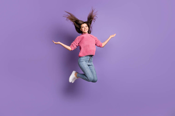 Full length body size photo of jumping woman throwing hair smiling wearing jeans pullover isolated on vibrant violet color background - Fotografie, Obrázek