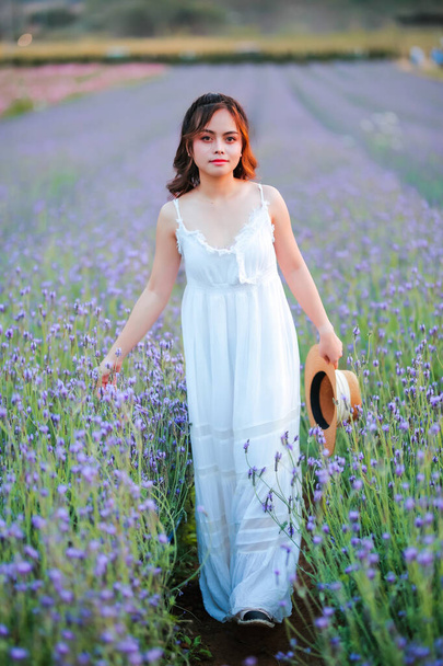 Blond long haired woman in lavender field. Style life enjoying journey to travel on vacation with relaxation with in long white dress outdoors on summer day. - Foto, Imagen