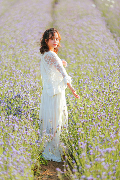 Blond long haired woman in lavender field. Style life enjoying journey to travel on vacation with relaxation with in long white dress outdoors on summer day. - Photo, Image