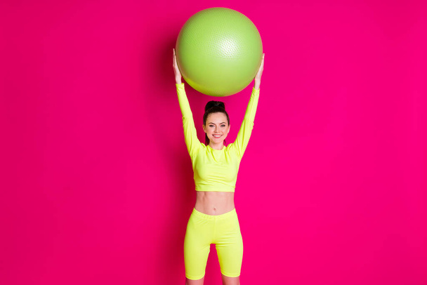 Photo of positive young sportswoman raise fit ball up isolated over pink shine color background - Photo, Image