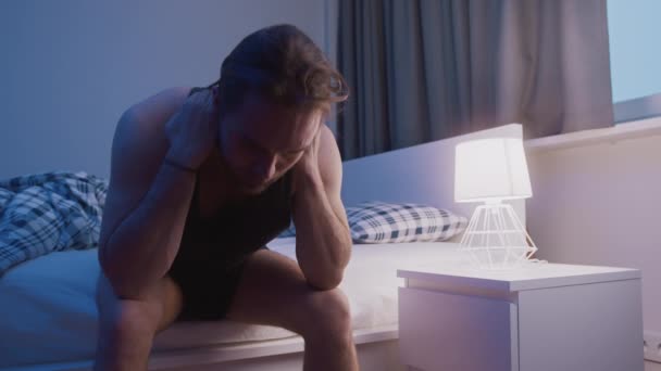Genç beyaz bir adam yatakta oturuyor ve saçını çekiyor. Uykusuzluk, zihinsel bozukluk ya da depresyon - Video, Çekim