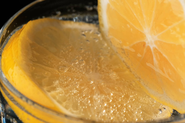 Carbonated lemonade with lemon in a transparent glass close-up macro photography - Foto, Imagem