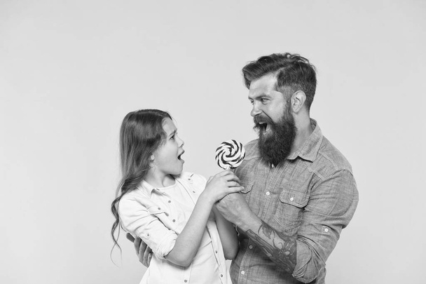 Happy family dad and daughter eat lollipop yellow background, funny battle concept - Foto, afbeelding
