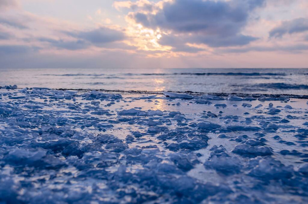 The frozen shore is covered with ice on the background of the sunset by the sea. Cold natural background - Valokuva, kuva