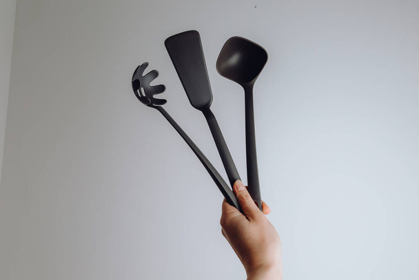 woman hand holding kitchen tools. Spatula, ladle, fork.  - Zdjęcie, obraz