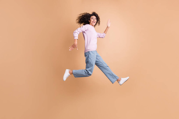 Full size profile photo of energetic person run jump open mouth rush speed isolated on brown color background - Фото, изображение