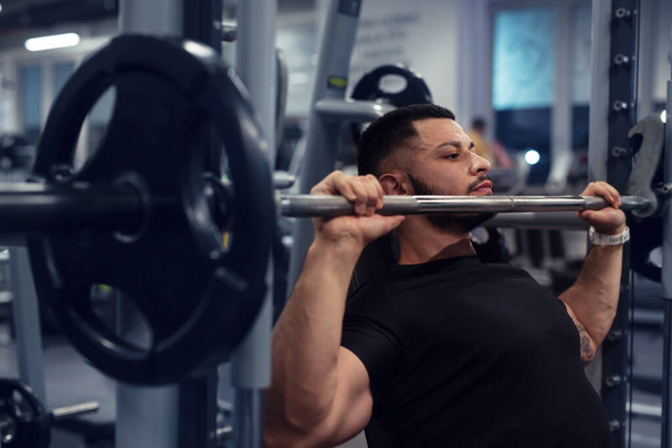 Bodybuilder working out in gym with determination - Фото, изображение