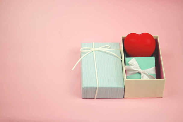 Red heart and small gift in blue present box on sweet pink background, giving love as a present on Valentine's day concept - Photo, Image