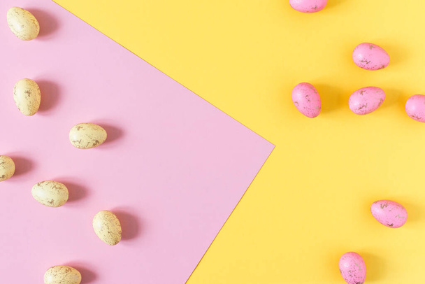 Uova di Pasqua gialle e rosa su sfondo rosa pastello e giallo vista dall'alto. Biglietto di auguri vacanze pasquali. - Foto, immagini