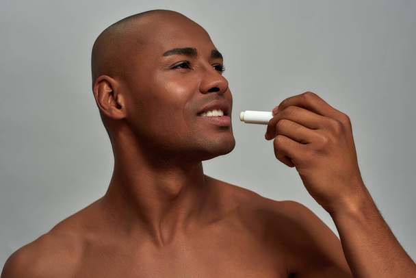 Hygienic lipstick spread across the lips of smiling male - Foto, imagen
