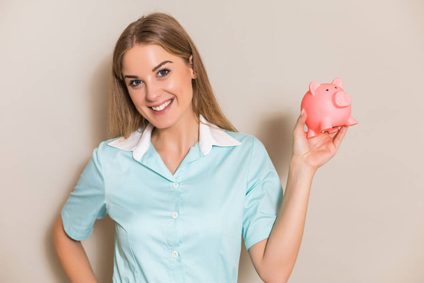 Portrait of nurse showing piggy bank. - Фото, изображение