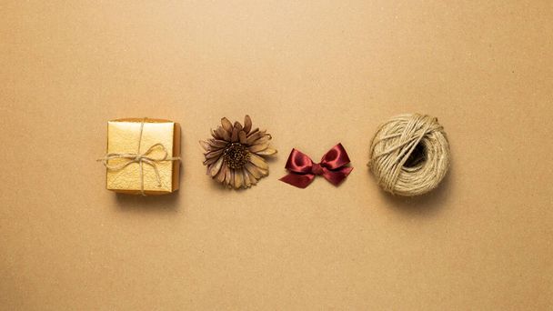 Gift box, dry flower, ribbon, string on brown kraft paper background. flat lay, top view, copy space - Photo, Image
