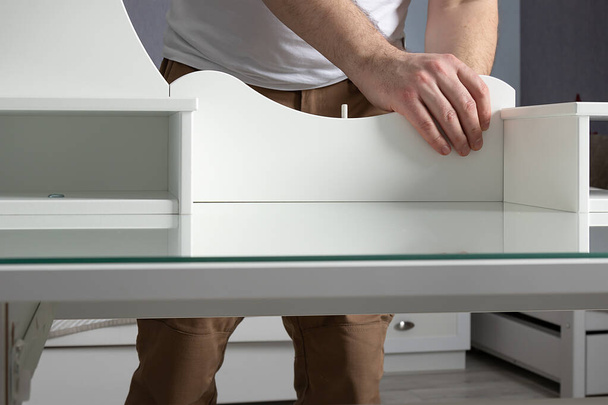 man collects white dressing table at home. Furniture assembly concept - Photo, Image