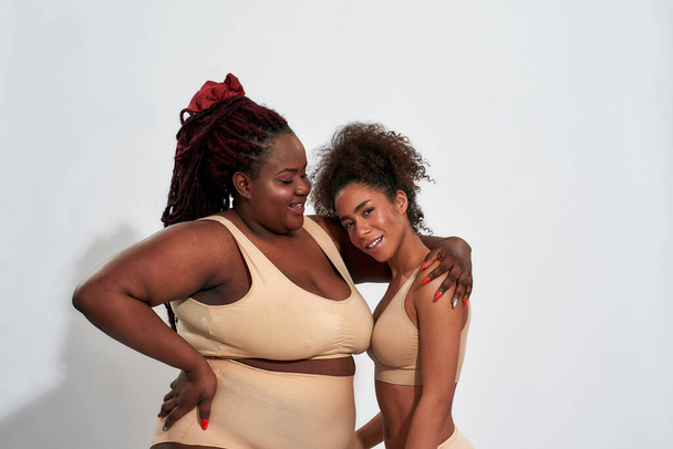 Happy young plump woman hugging with slim girl - Foto, afbeelding