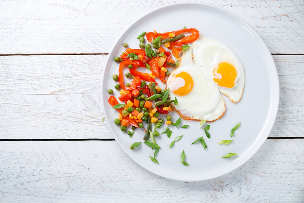 Fried eggs and vegetables in a white plat - Photo, Image