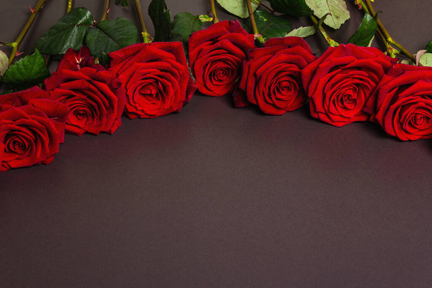 Μπουκέτο με φρέσκα τριαντάφυλλα μπορντό σε μαύρο φόντο από μπετόν. Αρωματικά κόκκινα λουλούδια, ιδέα για δώρο για την Ημέρα του Αγίου Βαλεντίνου, Γάμος ή Γενέθλια - Φωτογραφία, εικόνα