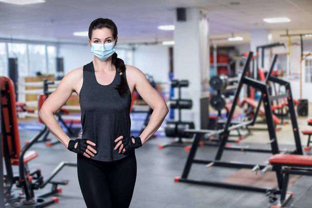 Fitness athlete stands in a mask on the background of the gym. - Photo, Image