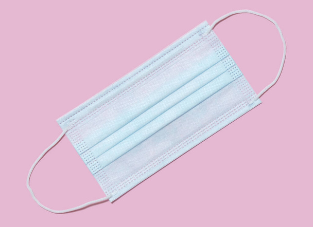 Medical disposable protective mask on a pink background. Covering the mouth and nose. Protection concept. - 写真・画像