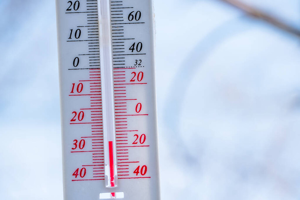 Το θερμόμετρο βρίσκεται στο χιόνι το χειμώνα και δείχνει αρνητική θερμοκρασία. Μετεωρολογικές συνθήκες σε ένα σκληρό κλίμα το χειμώνα με χαμηλή θερμοκρασία του αέρα και του περιβάλλοντος - Φωτογραφία, εικόνα