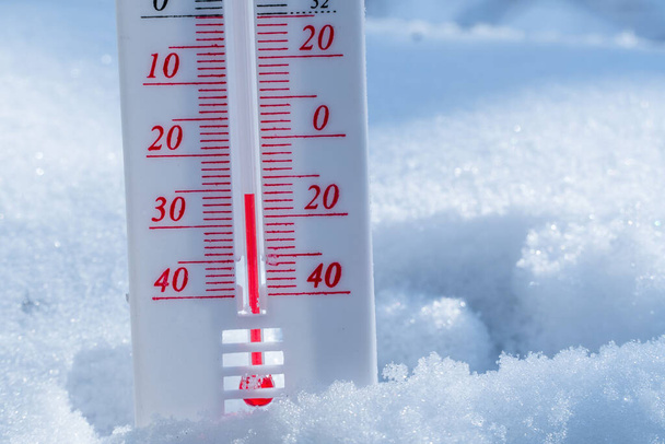 Le thermomètre se trouve sur la neige en hiver montrant une température négative. Conditions météorologiques dans un climat rude en hiver avec de l'air bas et des températures ambiantes. - Photo, image