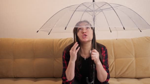 Wütende Frau ruft Klempner an, der sich unter Regenschirm vor Wasser versteckt - Filmmaterial, Video