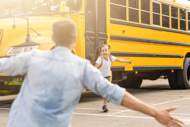 Otec potkává dcerušku, jak vystupuje ze školního autobusu. - Fotografie, Obrázek