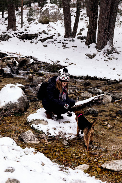 stock fotografie pořízena žena, která je na ostrově v řece volá svého psa, aby ji pohladil na den ve zasněžené hoře - Fotografie, Obrázek