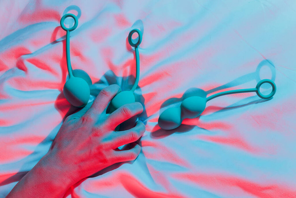 Woman holding anal balls in bed close-up. - 写真・画像