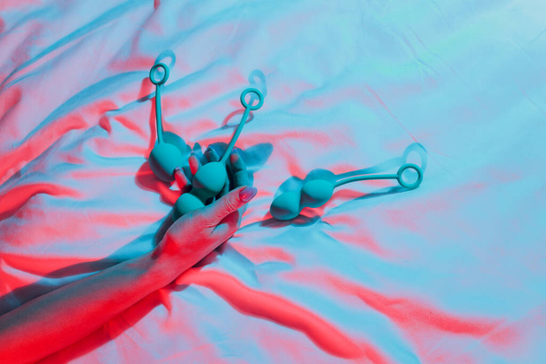 Woman holding anal balls in bed close-up. - Φωτογραφία, εικόνα