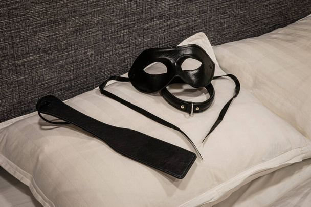 Paleta, cuello y máscara en la almohada. Disciplina doméstica. Instrumentos tradicionales de castigo corporal. BDSM - Foto, Imagen
