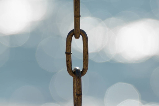 Detailní kovový řetěz z houpačky izolovaný na třpytivé vodě. Krásné rozostřené moře pozadí - Fotografie, Obrázek