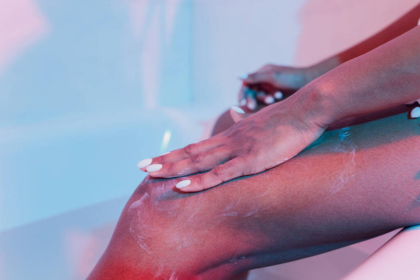 A woman applying moisturiser to her legs close-up. - Foto, Imagem