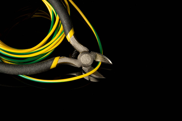 Wire cutters and wire closeup on black background. Electronics Repair Ide - Photo, Image