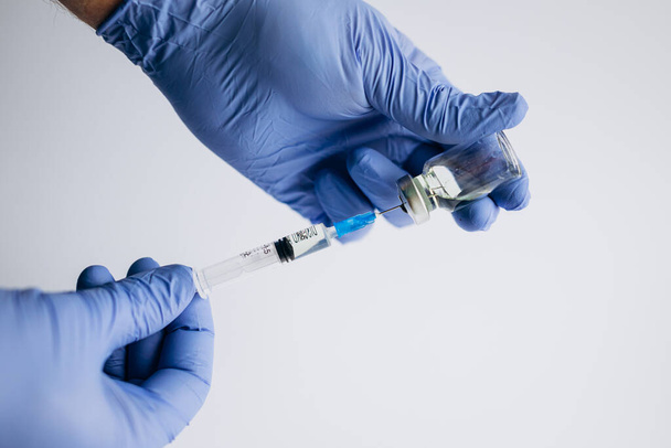 Γιατρός, νοσοκόμα, επιστήμονας χέρι σε μπλε γάντια κατέχει γρίπη, ιλαρά, coronavirus, covid-19 εμβολιασμό, προετοιμάζεται για τον εμβολιασμό ενός παιδιού, παιδί, ενήλικας, άνδρας και γυναίκα, ιατρική και φάρμακα έννοια. - Φωτογραφία, εικόνα