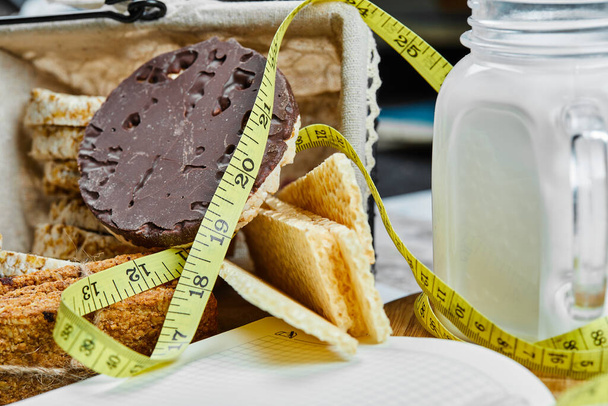 Biscuits and a jar of milk on a dark table with measure tape - Photo, Image