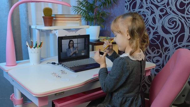 Κορίτσι παιδί σπουδάζει κατ 'οίκον εργασία με τη δασκάλα στον φορητό υπολογιστή κατά τη διάρκεια των online μαθημάτων στο σπίτι - Φωτογραφία, εικόνα