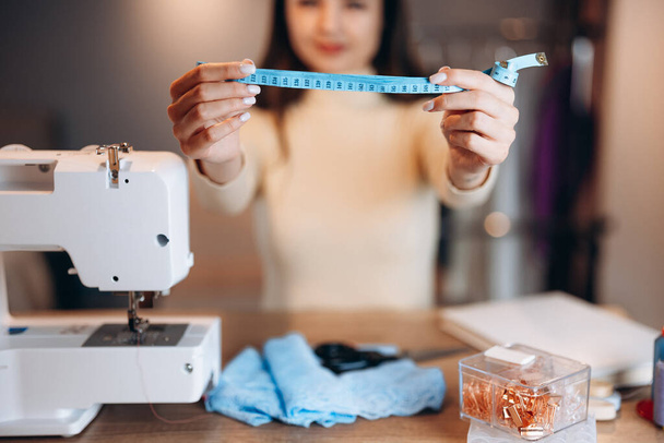 Primeros planos costurera medida de retención en el taller. Mujer joven modista con máquina de coser. Creación de cursos de diseño de ropa en línea. - Foto, Imagen