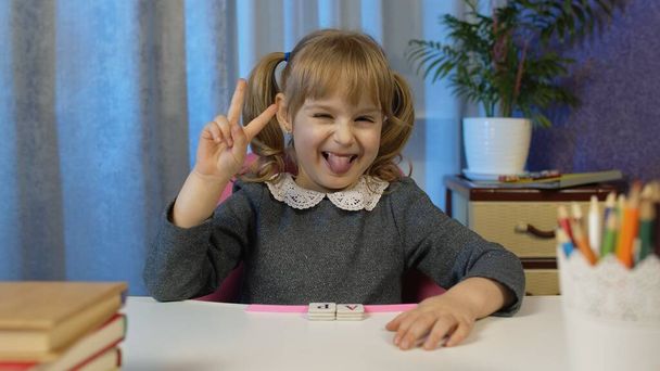 Gyermek lány nézi webkamera videohívás, tanul leckéket otthon, mosolygós bemutató nyelv - Fotó, kép