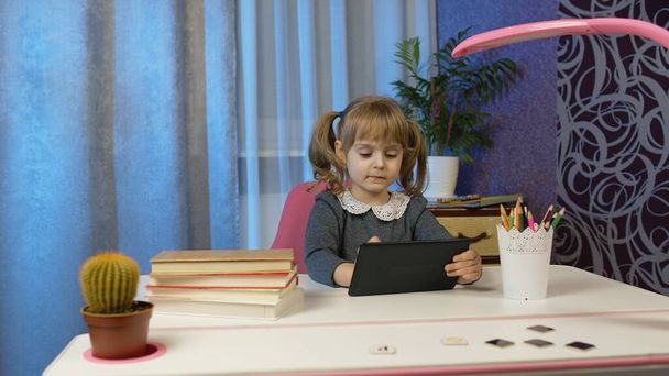 Studentessa bambino lezioni di apprendimento, l'istruzione a distanza a casa seduto a tavola con computer portatile - Foto, immagini