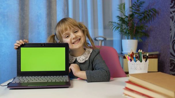 Niña con portátil mirando en la pantalla verde en casa, lecciones de distancia en línea educación de los niños - Foto, Imagen