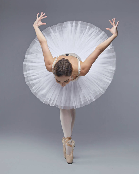 attractive ballerina poses gracefully in the studio on a white background - Zdjęcie, obraz