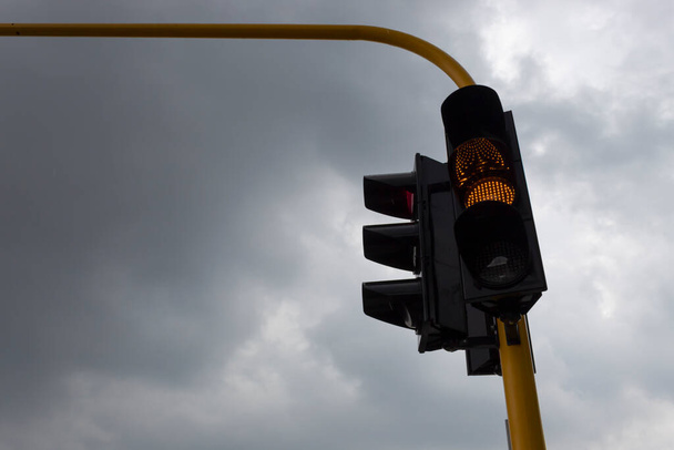 Semáforo amarillo con día gris y lluvioso al fondo. Concepto de tráfico - Foto, Imagen