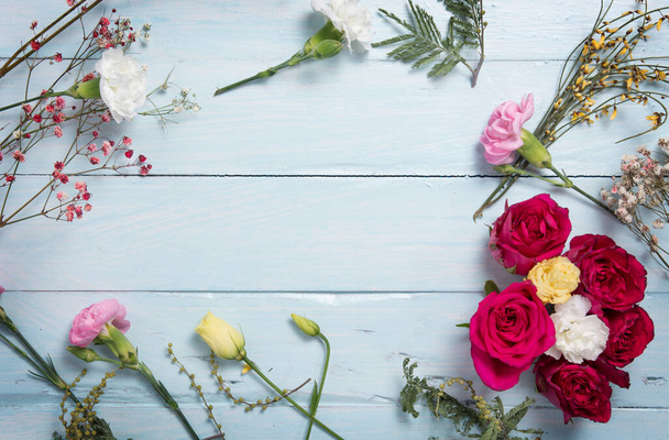 Розы и белые цветы вместе с декоративными растениями образуют композицию на деревянных сине-белых досках. скопировать пространство. Плоская постель. - Фото, изображение