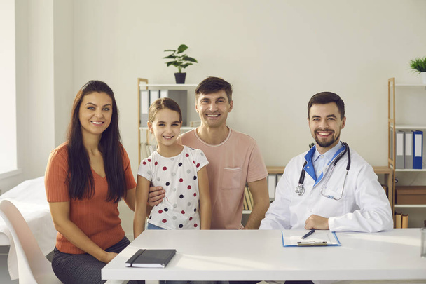 Portrait of happy young mother, father and child together with their family doctor - Фото, зображення