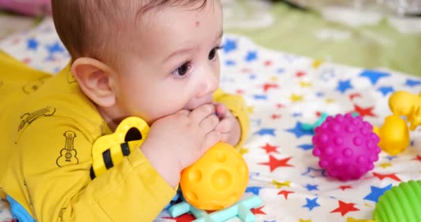Bebek, çocukluk konsepti. Gülümseyen mutlu bebeğin ip ile oynadığı yakın plan. Diş kesimi. İlk dişler. Neşesiz dişsiz 7 ay bebek ısırığı, kemiren oyuncak - Video, Çekim