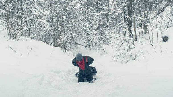 Man with a stretcher behind him kneels in the Siberian taiga - Photo, Image
