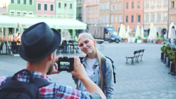 Вид ззаду чоловіка, що робить фотографії жіночого туриста на площі міського ринку
 - Фото, зображення