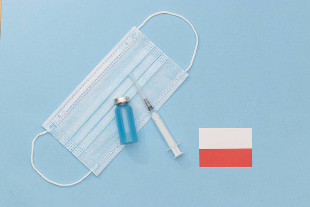 Transparent medical ampoules, stethoscope, syringe and protective mask on a light blue background. medicine, vaccination against covid-19. Protection during a pandemic. vaccination in Poland, - Photo, Image