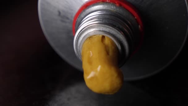 Macro shot van gele mosterd stroomt uit een buis, concept van ontlasting - Video